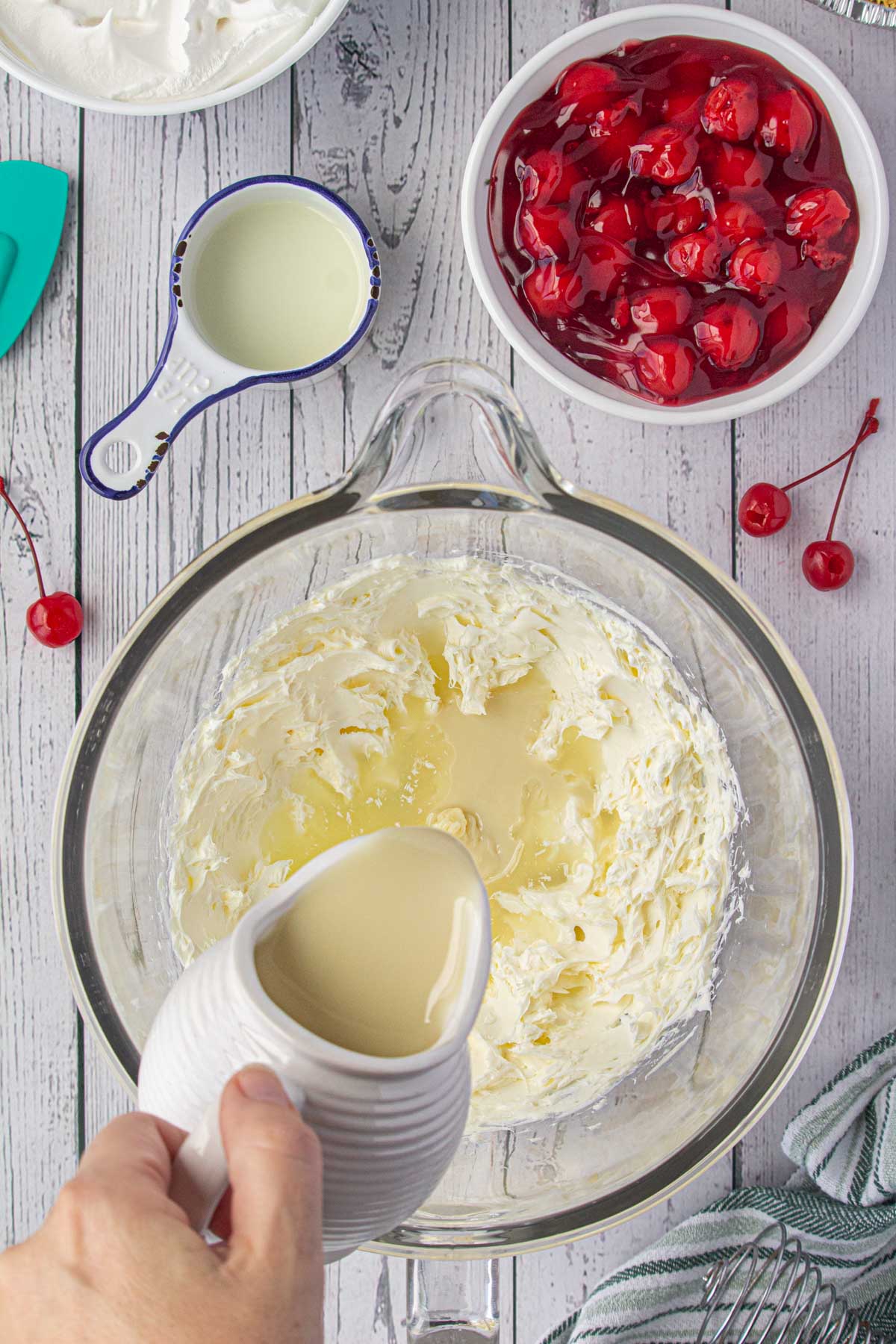 Pouring sweetened condensed milk into the cream cheese.