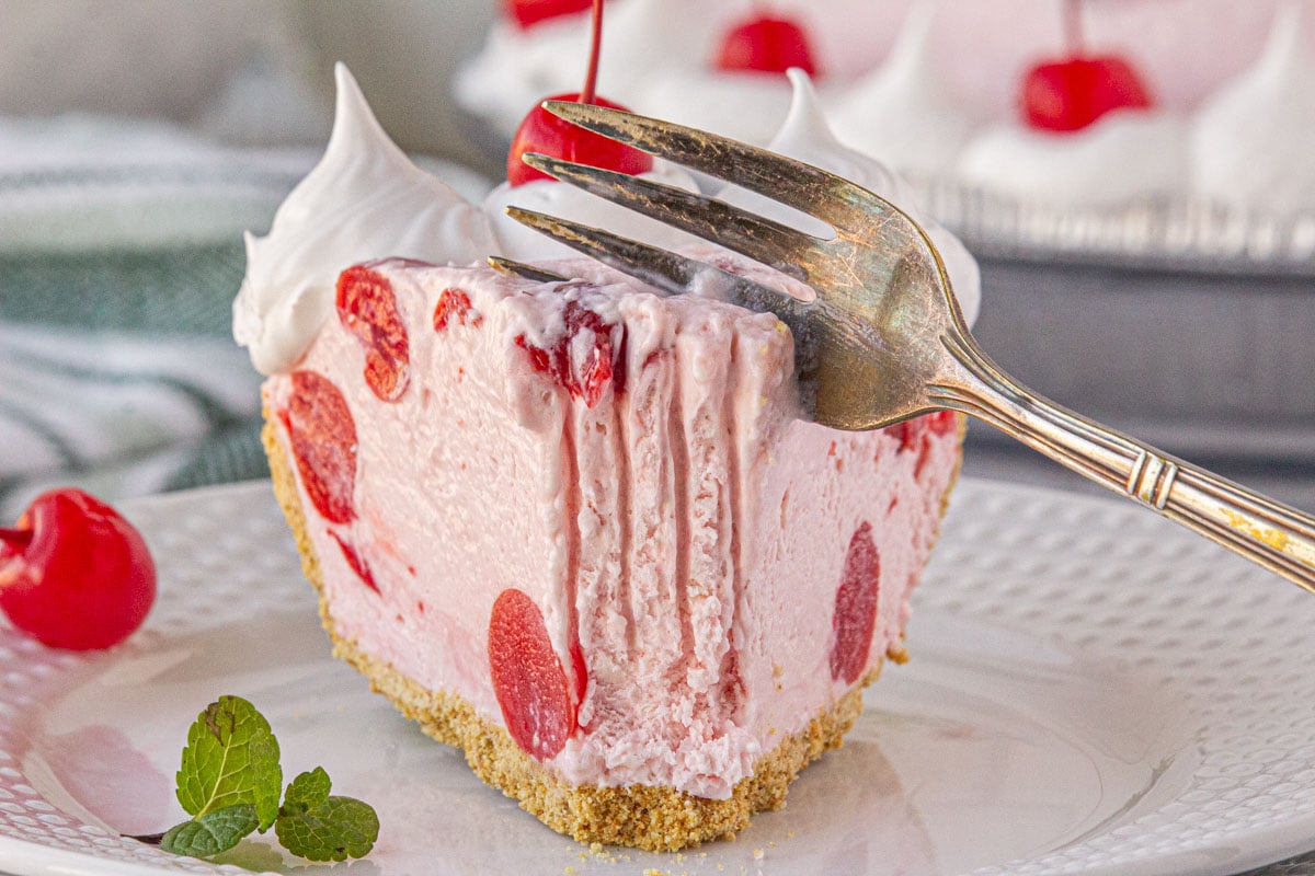 Slice of cherry icebox pie being cut with a fork.