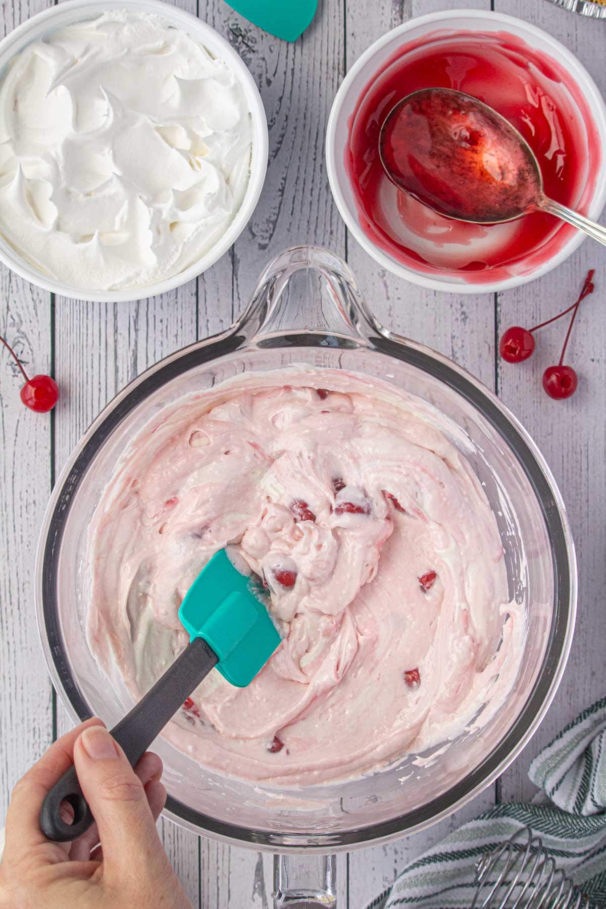 Stirring the cherry pie filling into the cream cheese mixture.