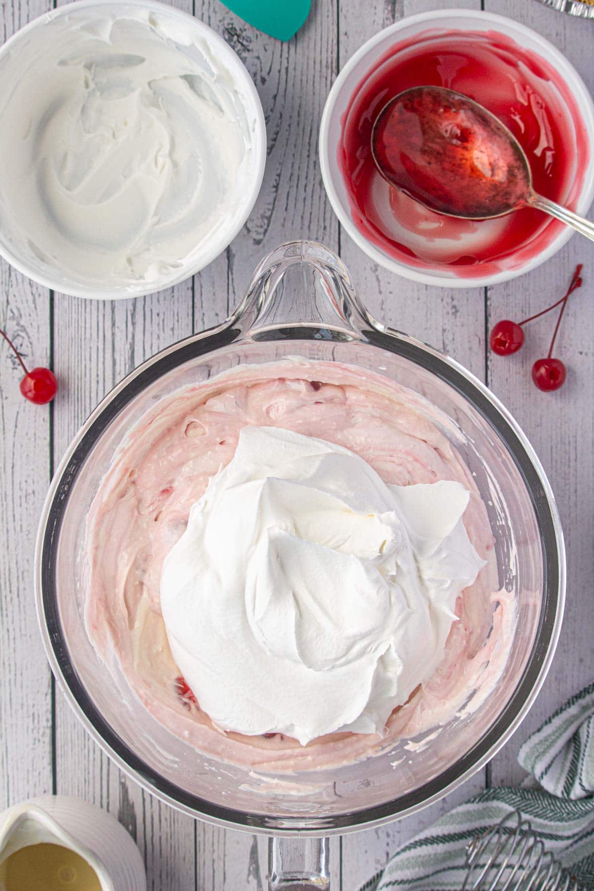 Folding the Cool Whip into the cherry pie mixture.