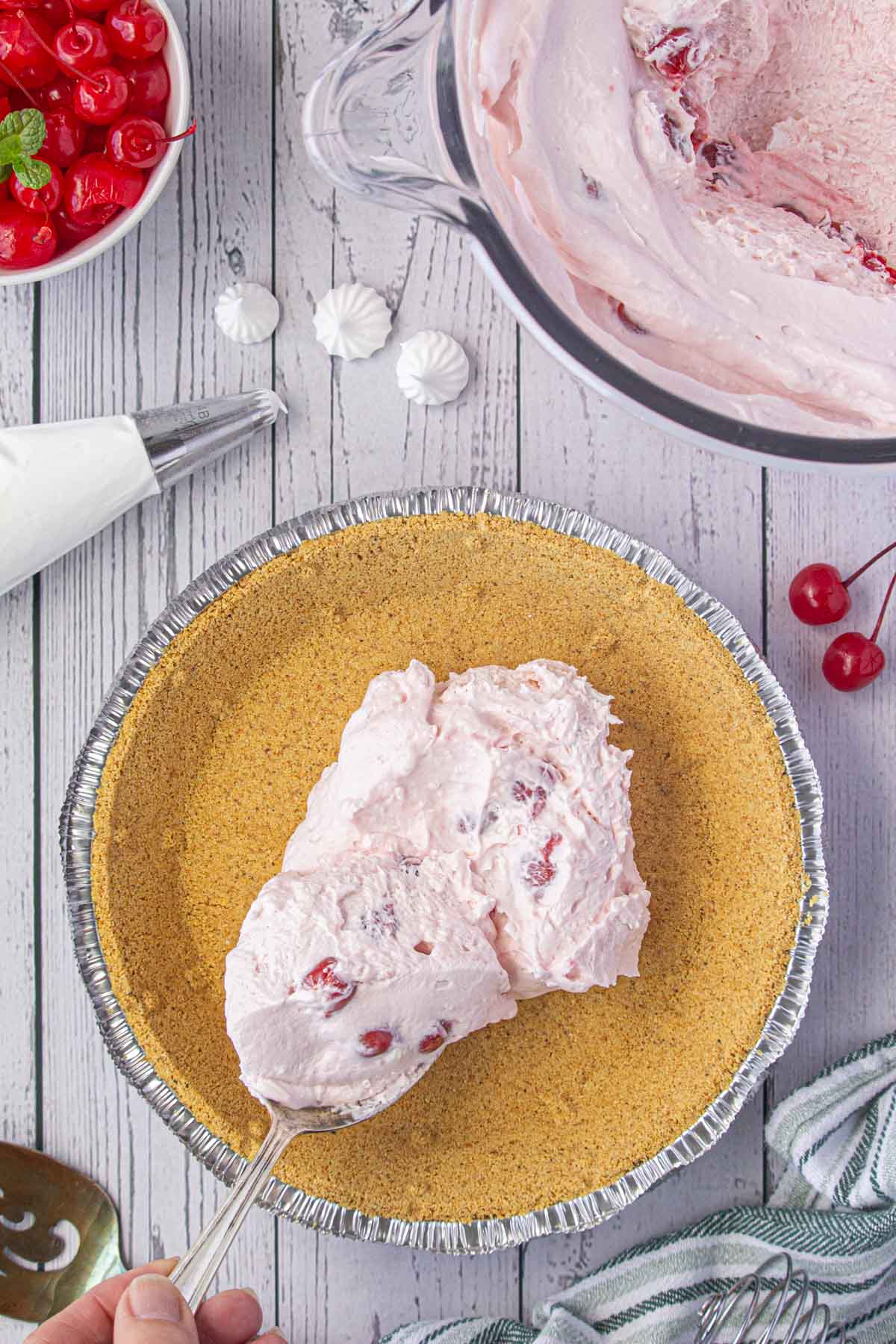 Spreading the cherry pie filling into the graham cracker crust.