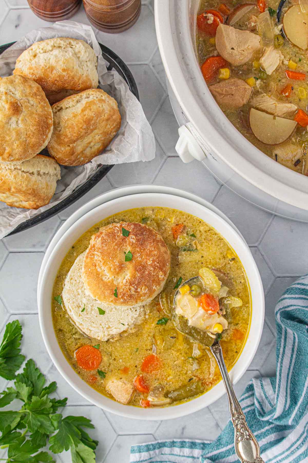 An overhead view of easy chicken pot pie soup in a dinner bowl with a biscuit on top.