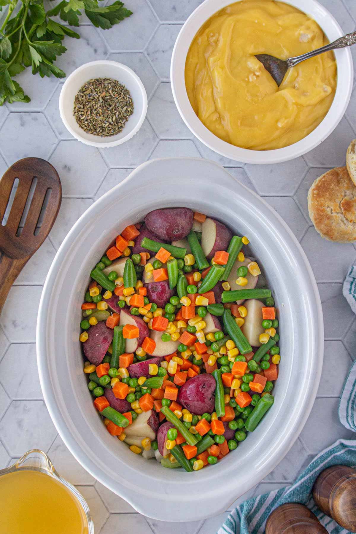 Adding the potatoes and vegetables to the crockpot.