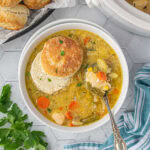 Overhead view of chicken pot pie soup recipe with a sliced biscuit floating on top.