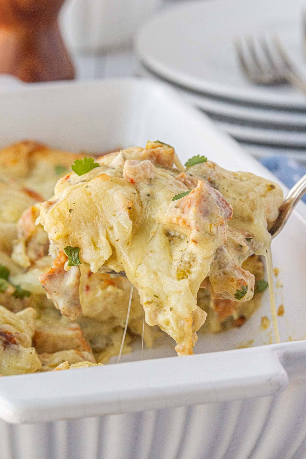 An angled view of a fork scooping chile chicken bubble up bake from the casserole dish.