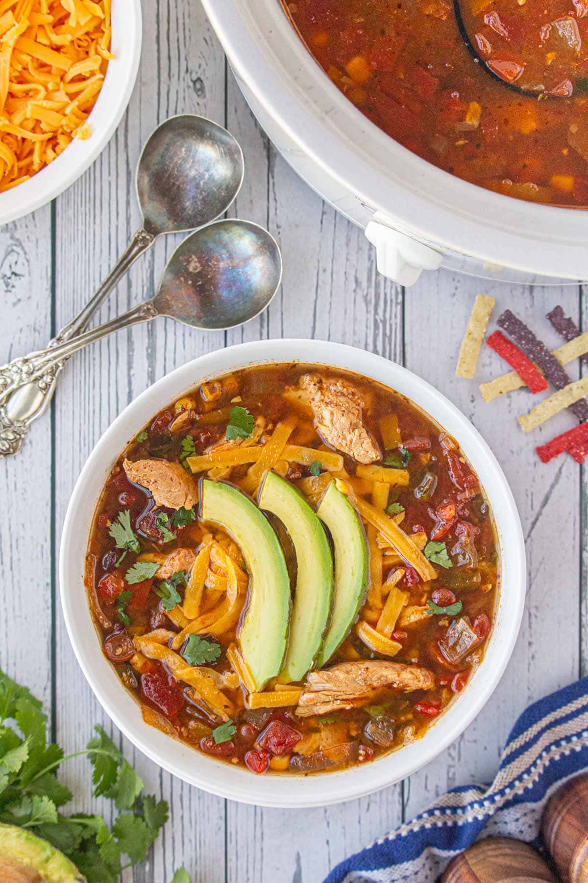 Overhead view of a bowl of fajita chicken soup with sliced avocado and cheese on the top.