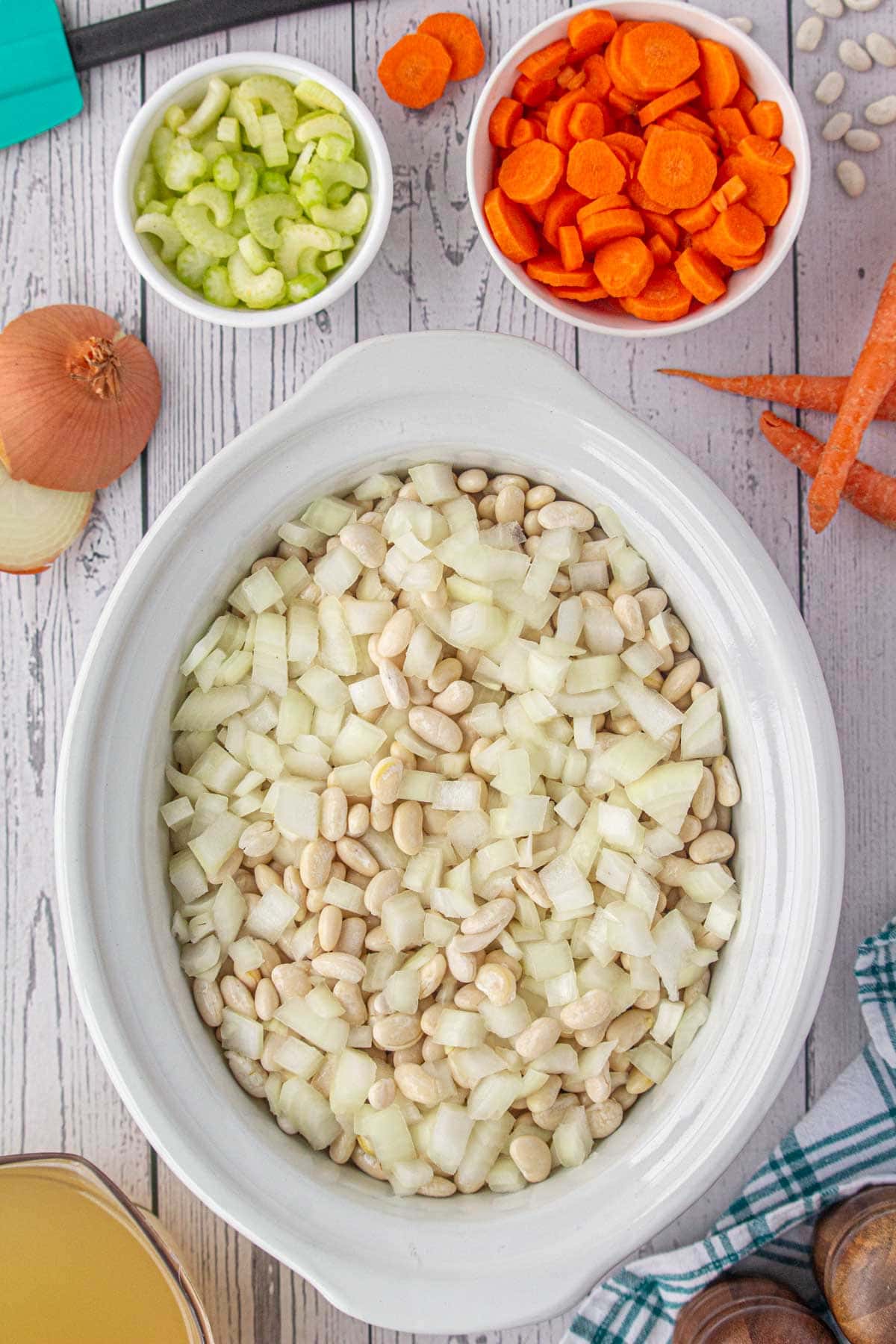 Adding the beans and onions to the slow cooker.