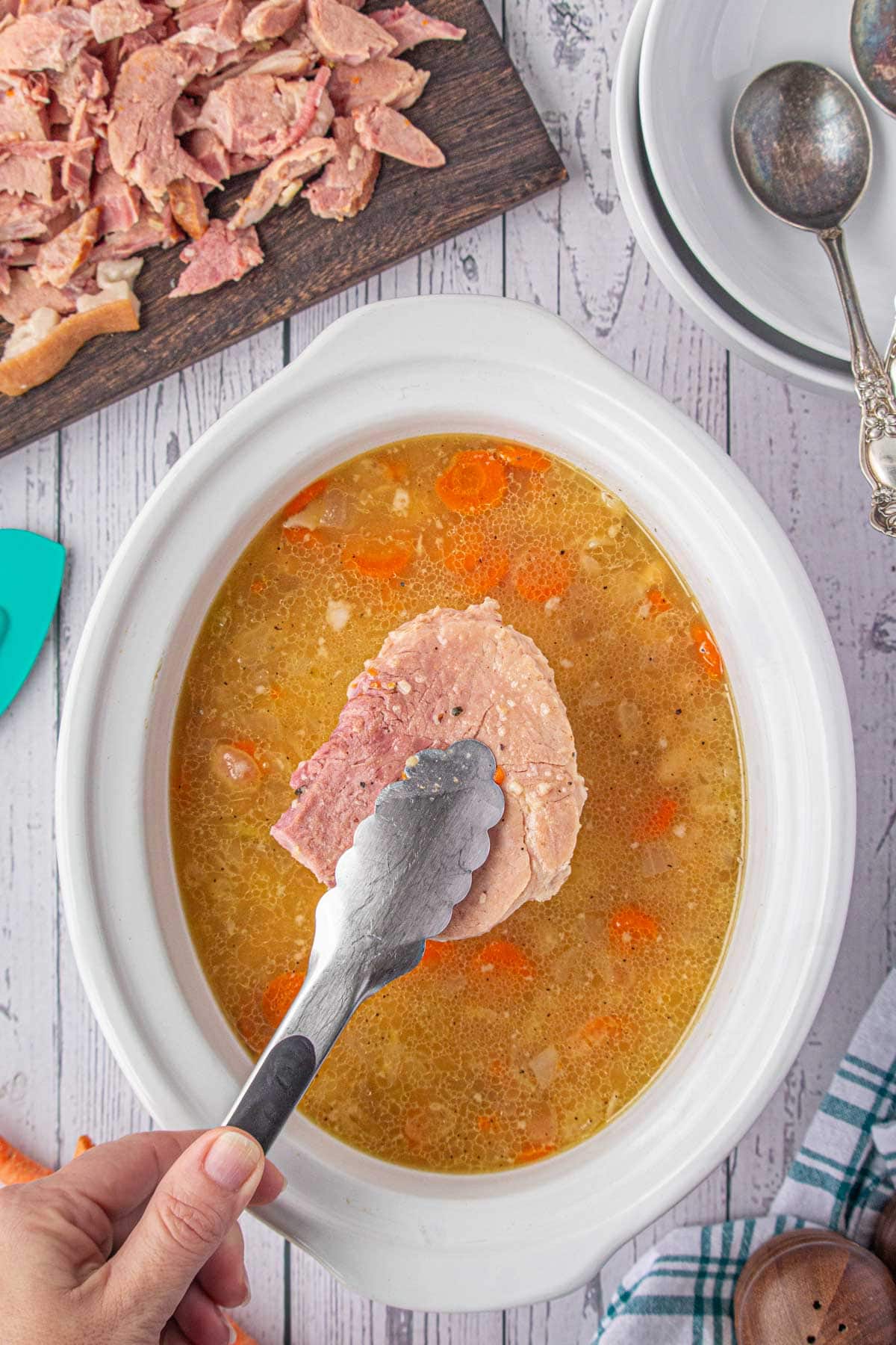 Removing the ham from the slow cooker to shred.