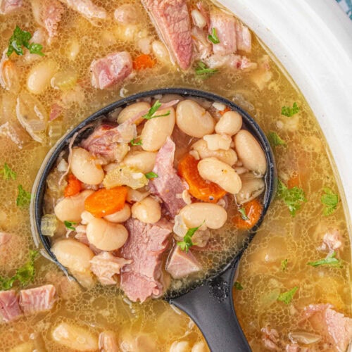 Overhead view of ham and bean soup being ladled out of a crockpot.