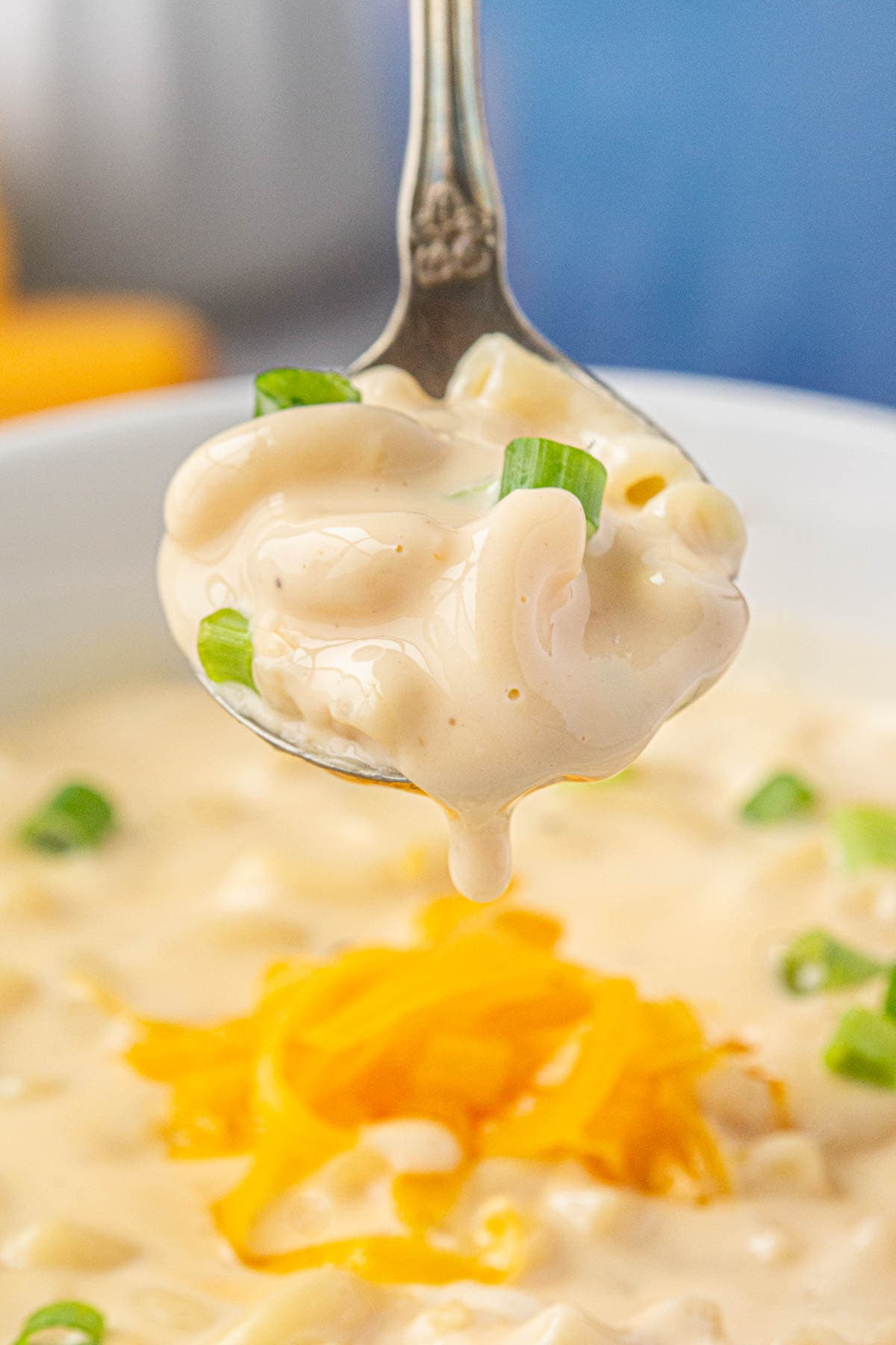 An up-close view of creamy macaroni and cheese soup on a spoon.