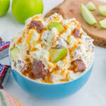 Mixed Snickers bars, green apples, and Cool Whip in a blue bowl.