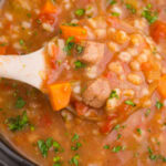 Beef and barley soup being ladeled out of the pot with a title text overlay for Pinterest.