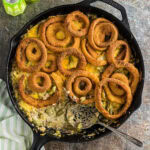 Overhead view of ground beef and green bean casserole with crispy onion rings on top.