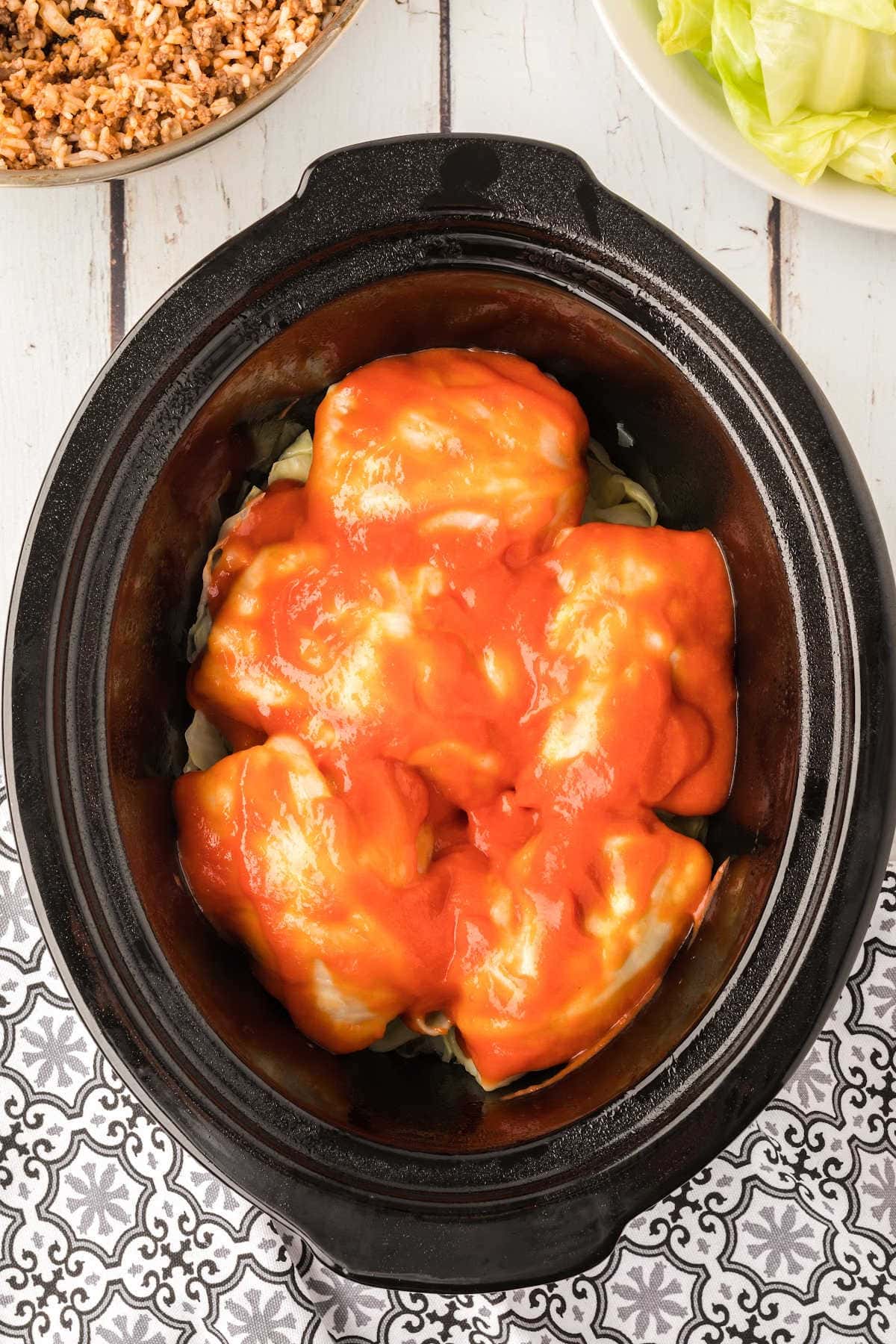 Cabbage rolls in slow cooker covered with sauce.