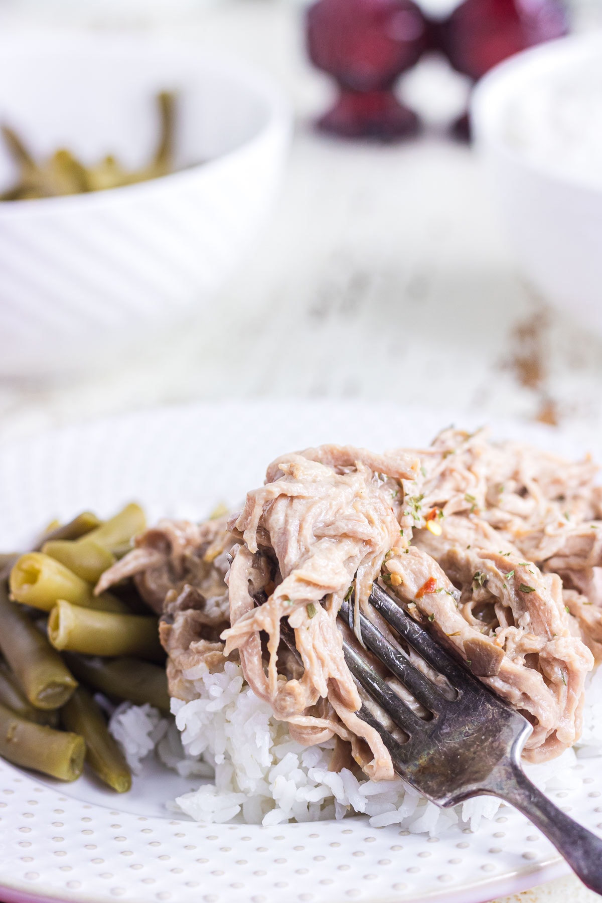 An up-close view of creamy slow cooked pork tenderloin over rice with green beans.