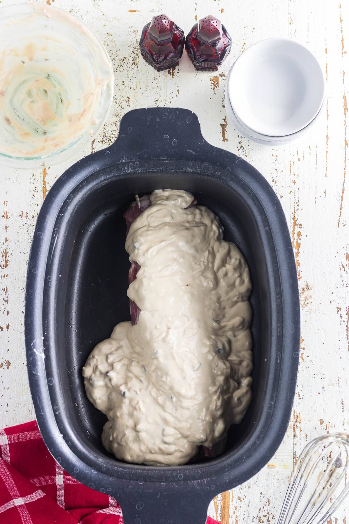 The pork tenderloin in the slow cooker covered with the sauce.