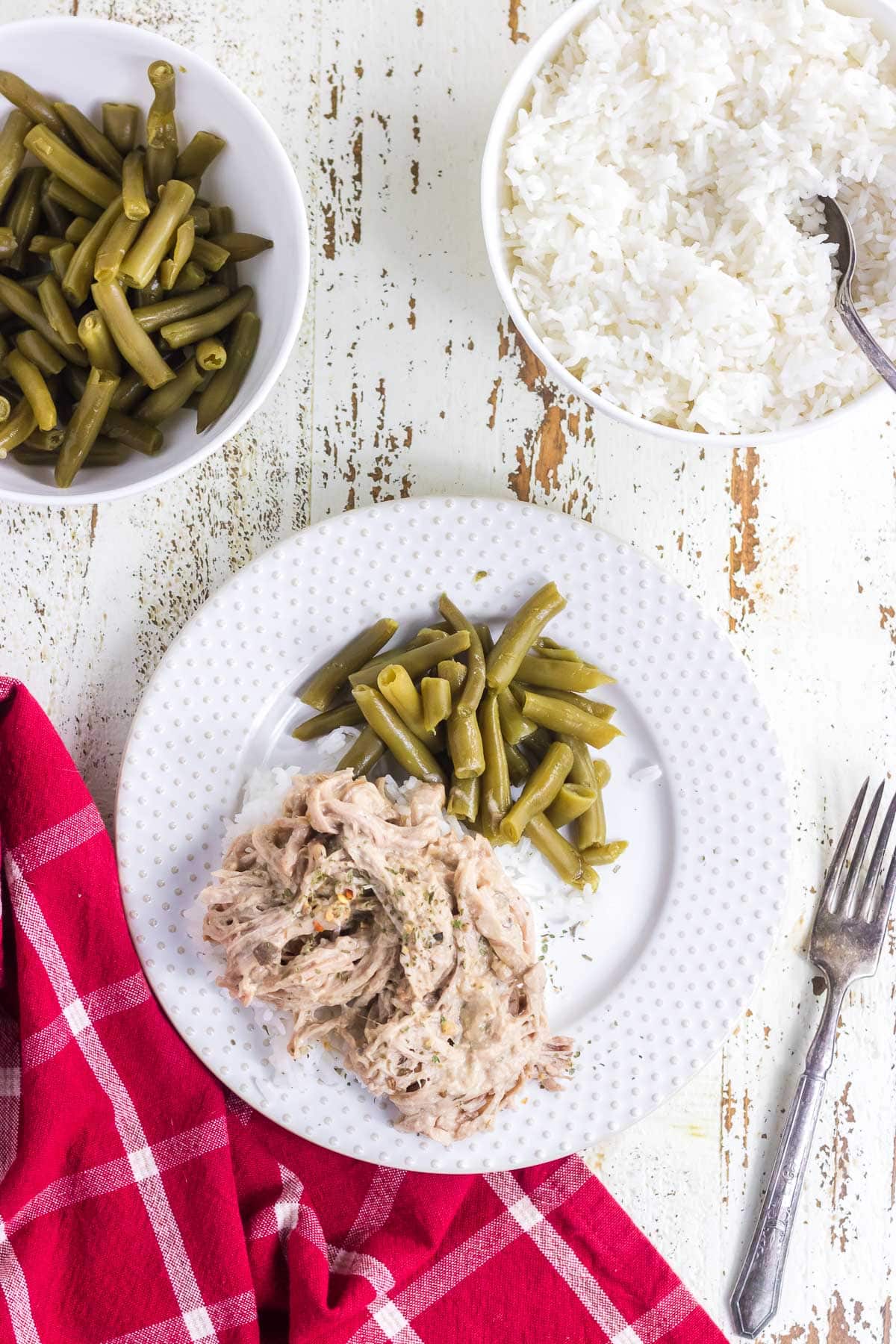 An overhead view of creamy slow cooked pork tenderloin on a plate with green beans.