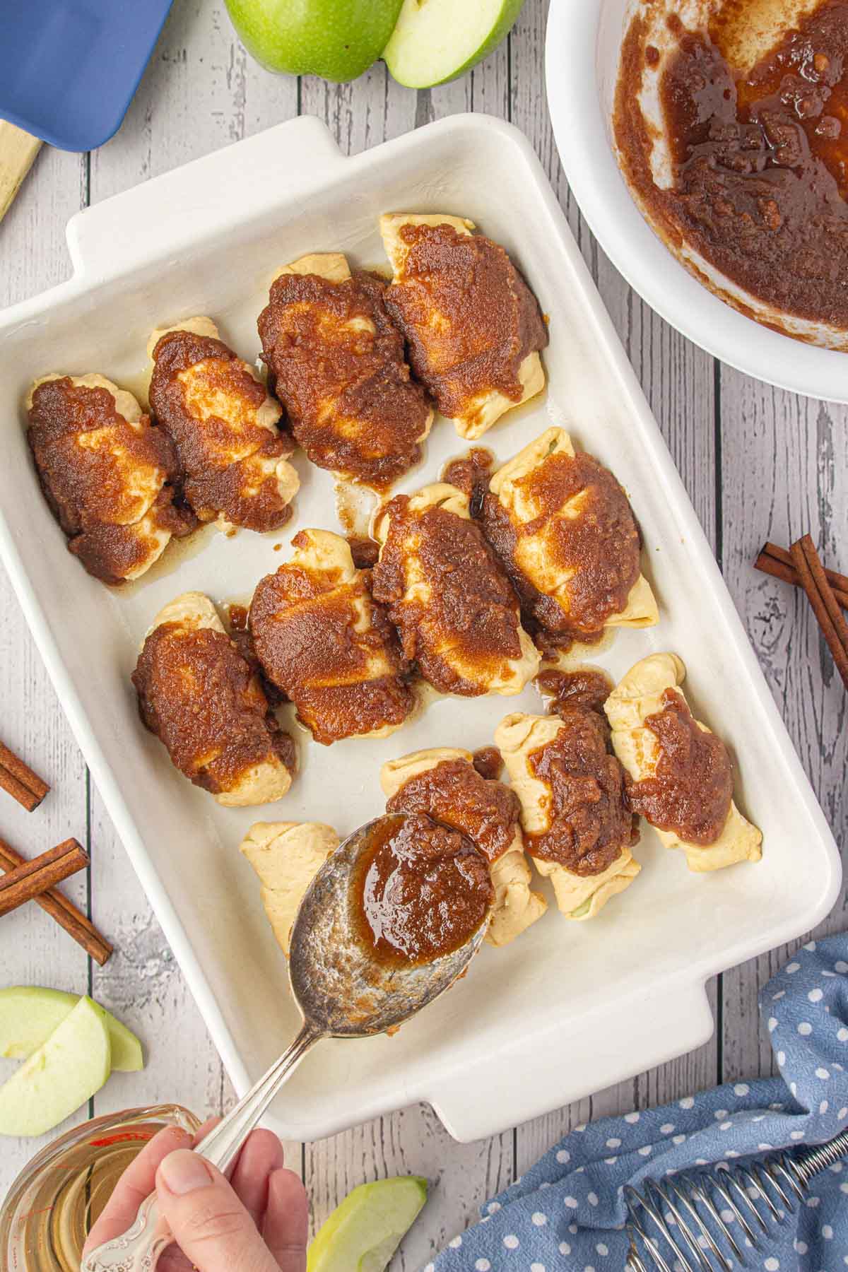 Spooning the brown sugar and butter mixture over the crescent roll dumplings.