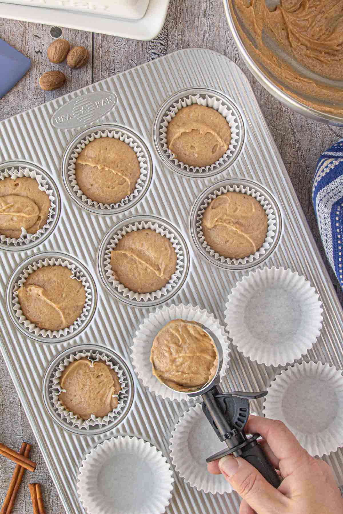 Scooping the French breakfast puff batter into a lined muffin tin.