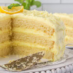 Lemon layer cake with a slice removed to show the layers of cake and filling.