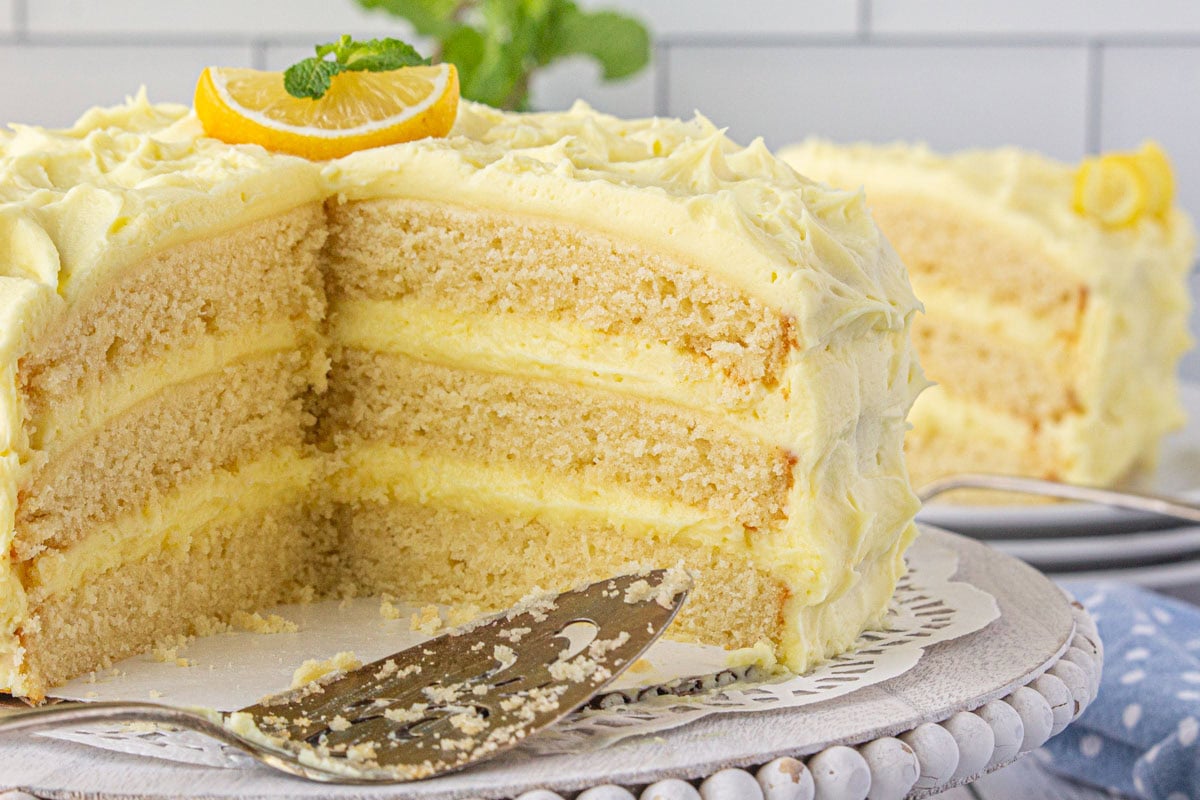 Lemon layer cake with a slice removed to show the layers of cake and filling.