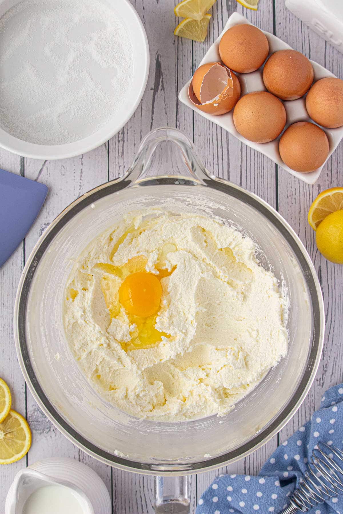 Adding the eggs, lemon juice, lemon extract, and lemonade mix to the creamed butter.