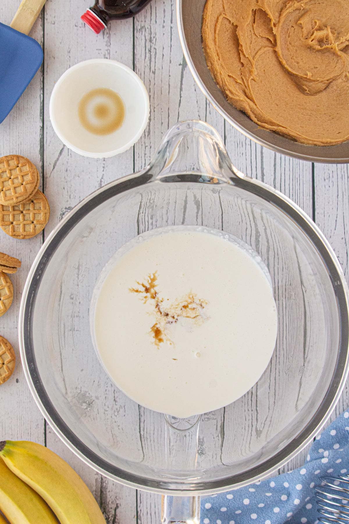 Heavy cream and vanilla in a glass mixing bowl.