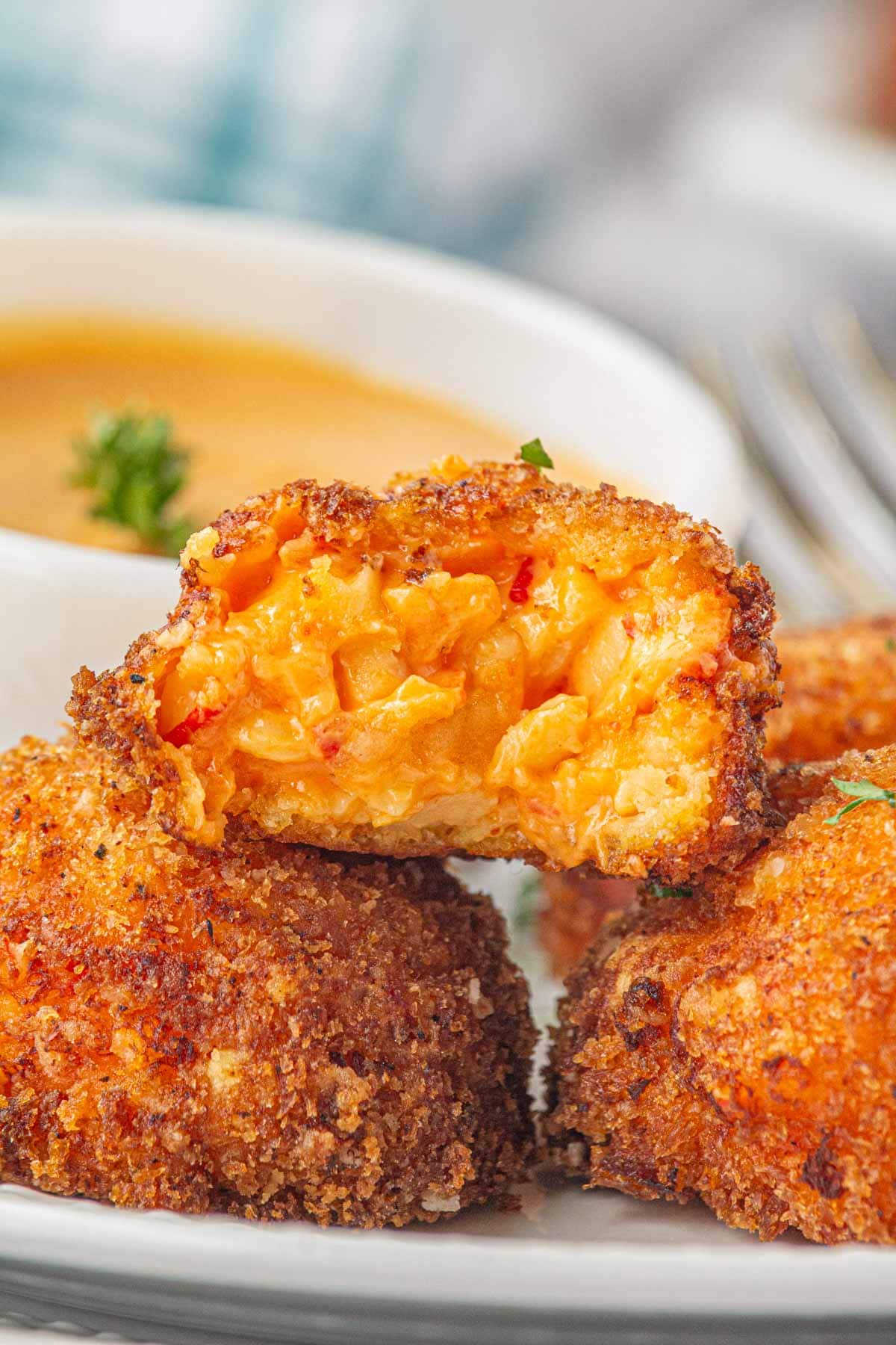 A close-up view of crispy fried pimento cheese balls; one has a bite removed.