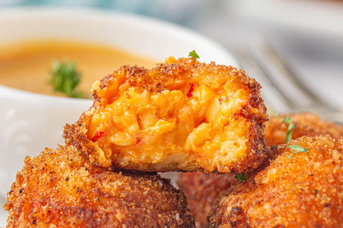 Closeup of pimento cheese balls cut in half to show the gooey cheese insides.