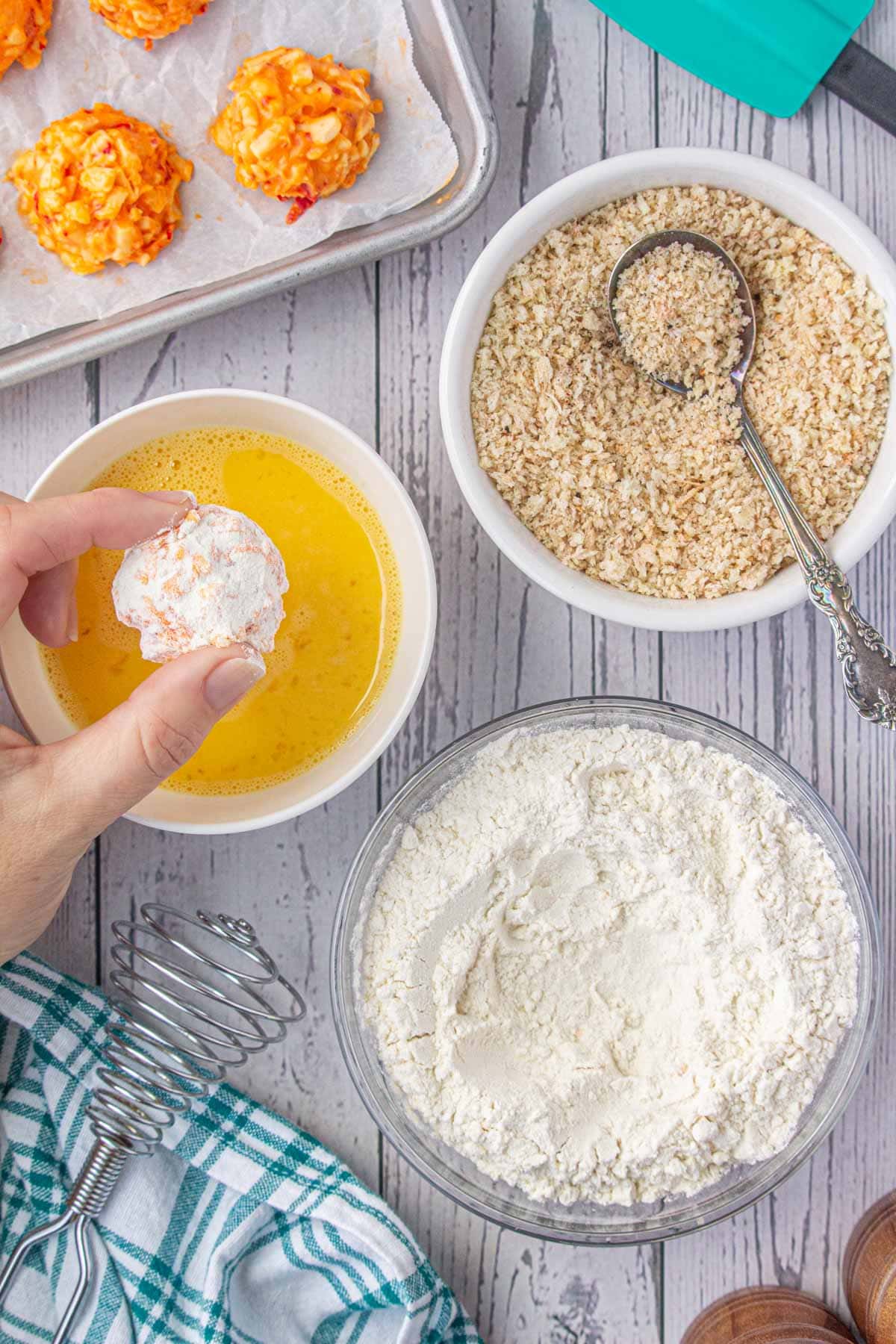 Dipping the flour-coated pimento cheese ball in egg.