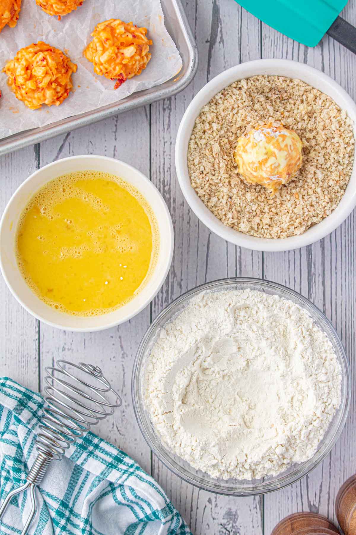 Rolling the battered pimento cheese ball in breadcrumbs.