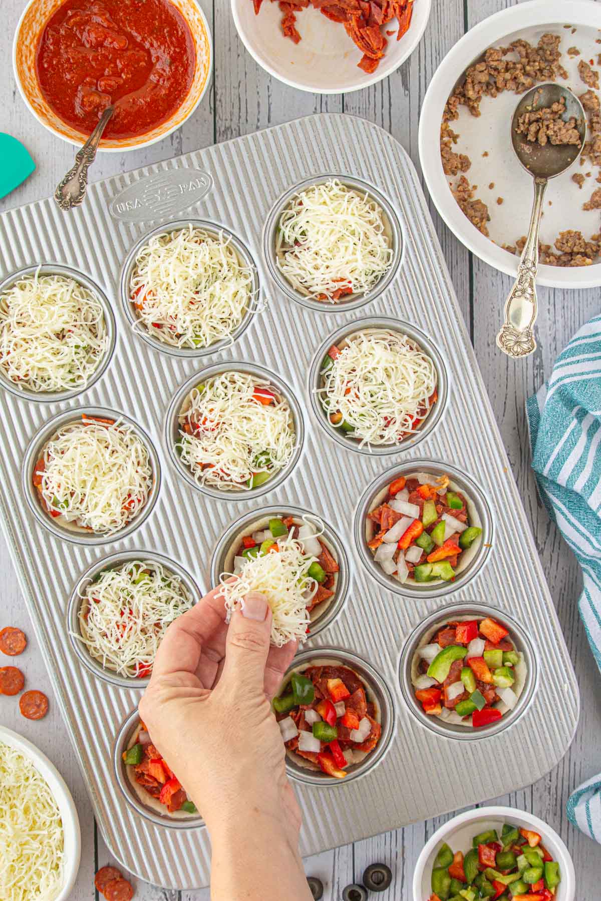 Adding cheese to the pizza cups.