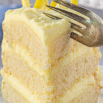 A fork cutting a slice of lemon layer cake with a title text overlay for Pinterest.